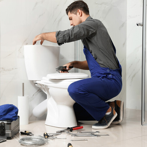 Professional plumber working with toilet bowl 