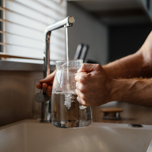 Close up of a man pouring water in the jug